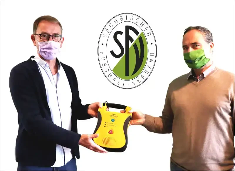 zwei Herren vom SFV präsentieren einen Defibrillator