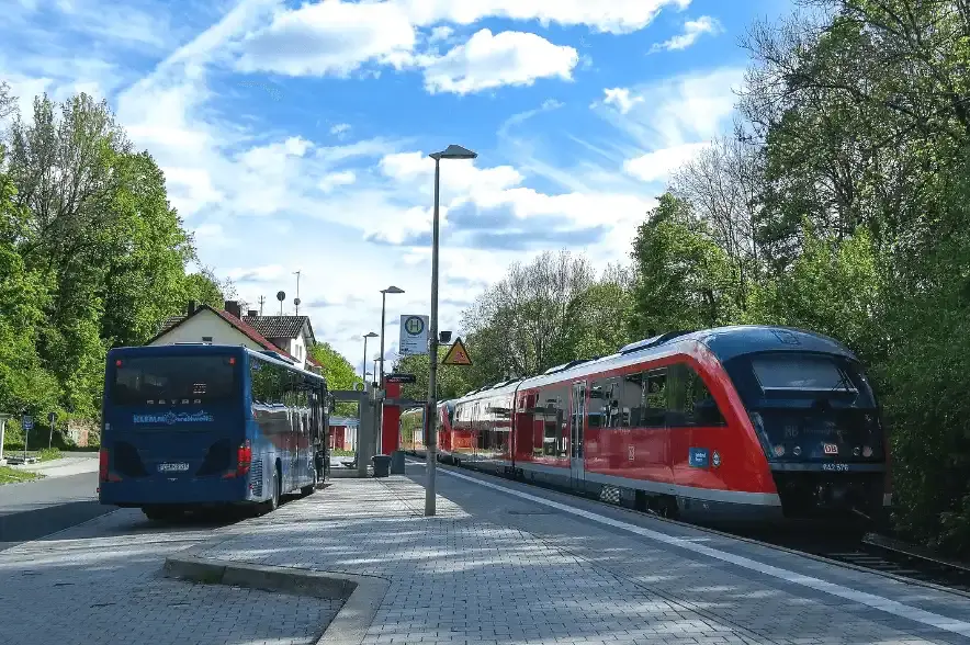 Haltesstelle mit Bus und Zug, blauen Himmel und Bäumen