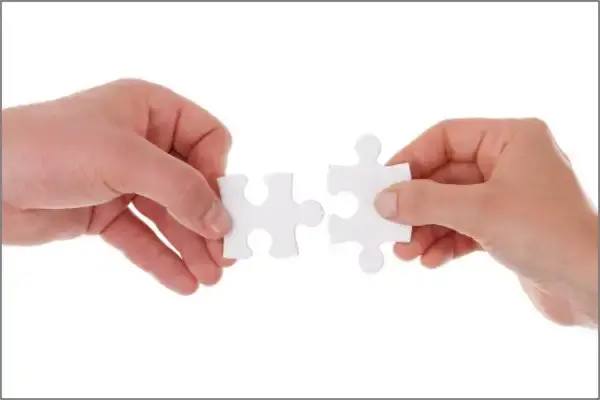 zwei Hände mit je einem zueinander passenden Puzzleteil