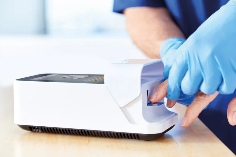 Medizinisches Fachpersonal führt mit LumiraDx einen Bluttest am Patienten mittels Fingerstich mit nur einem Tropfen Blut durch