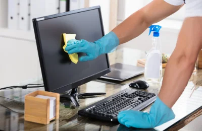 Mann putzt Bildschirm im Büro